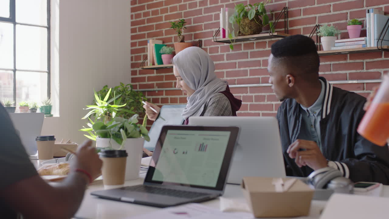 young muslim business woman using tablet computer sharing creative ideas presenting project showing colleagues in office meeting diverse team working together brainstorming planning strategy