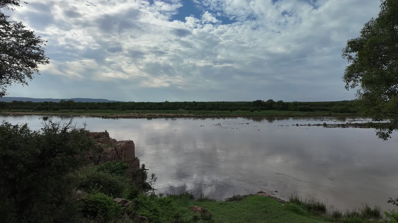 Panning timelapse next to flowing river with cloud reflections in Kruger Park