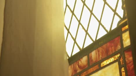 slow motion pan down of white curtain over stained glass window in a historic church