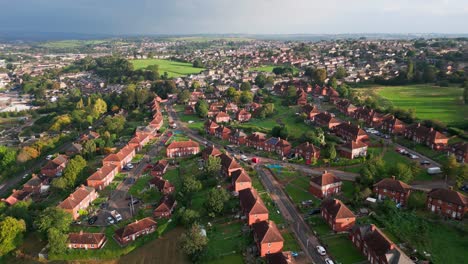 Urban-housing-in-the-UK:-Aerial-view-of-a-council-run-estate-in-Yorkshire,-marked-by-red-brick-buildings,-the-morning-sun,-and-a-thriving-community