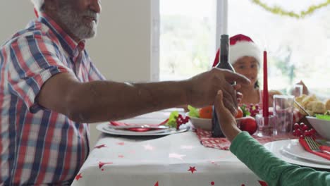 Glückliche-Afroamerikanische-Mehrgenerationenfamilie,-Die-Weihnachtsmützen-Trägt-Und-In-Der-Küche-Feiert