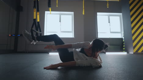 doing trx exercises. young athletic woman in sports clothing training legs with trx fitness straps in the gym. exercise where stabilizing muscles trained and the whole body is working truly functional