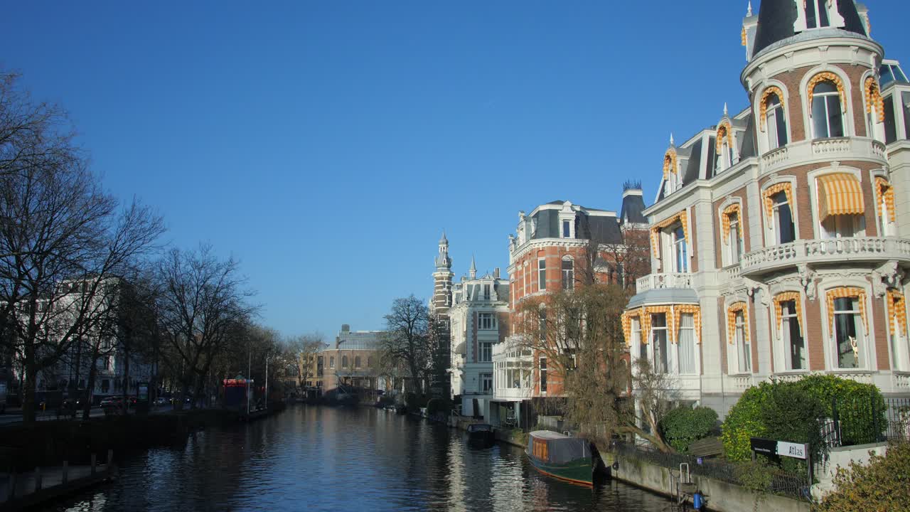 네덜란드 암스테르담의 뮤지엄브루그 다리에 있는 웨터링스찬스 운하의 전통 저택 위에 푸른 하늘