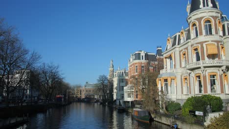 Blue-Sky-Over-Traditional-Mansions-At-Weteringschans-Canal-In-Museumbrug-Bridge-In-Amsterdam,-Netherlands