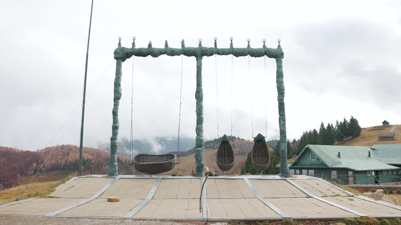 Large Artistic Outdoor Swing Set At Mountain Resort Amfiteatrul Transilvania In Romania. wide shot