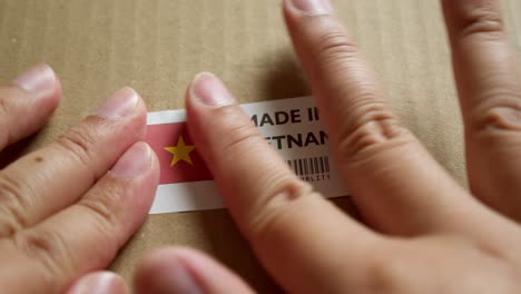 hands applying made in vietnam flag label on a shipping box with product premium quality barcode