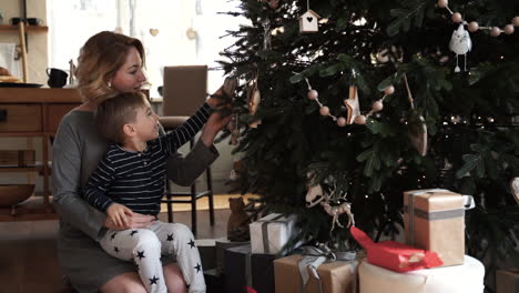 madre e hijo decoran juntos el árbol de navidad