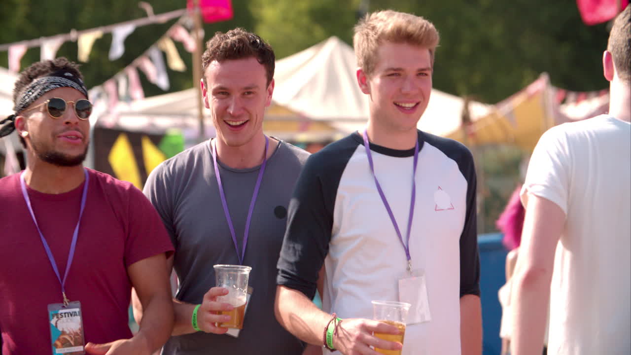 Tre mandlige venner går på en musikfestival, slowmotion.