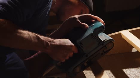 man sanding wood with a belt sander