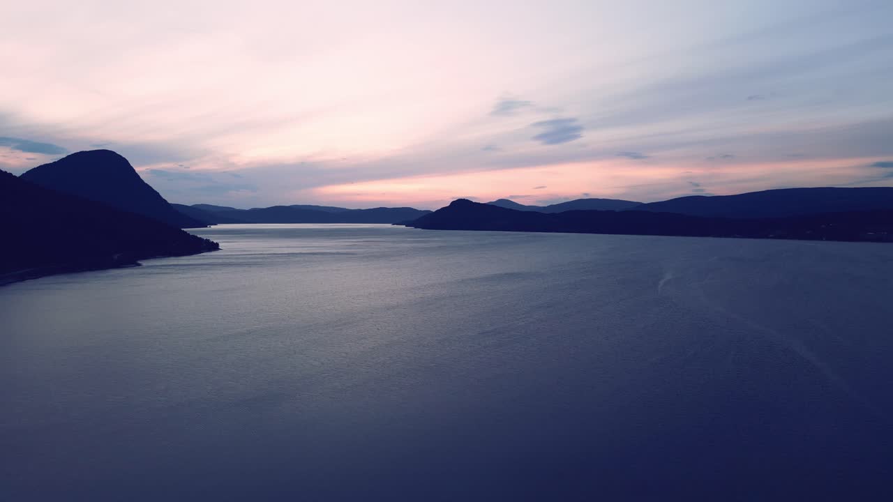 volando sobre el océano muy tranquilo en el norte de europa noruega al atardecer con las montañas reveladas mientras pasa el océano con sus olas