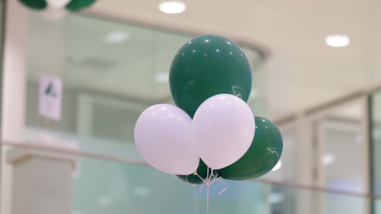 globos verdes y blancos atados dentro de una oficina corporativa durante un evento