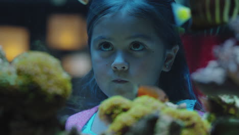 happy girl in aquarium looking at fish curious child watching colorful marine life swimming in tank learning about sea animals in underwater ecosystem inquisitive kid at oceanarium