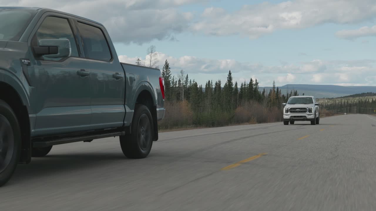 Two Ford F-150 Trucks Driving on a Scenic Highway