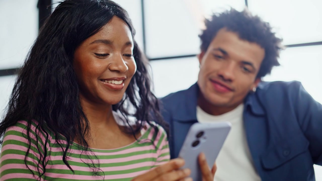 Diverse couple looking smartphone sitting home closeup. Man woman ordering goods