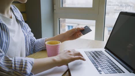 mujer comprando en línea a través de una computadora portátil