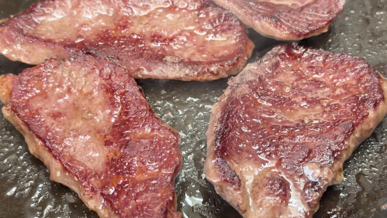 Primo piano di bistecche di manzo Wagyu marmorizzato sfrigolanti e rosolate in una padella calda
