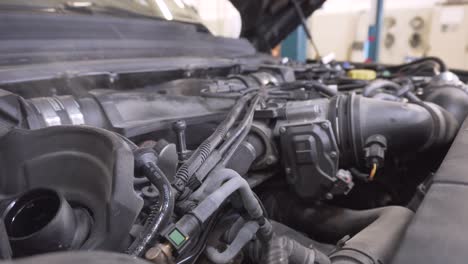 car mechanic looking for a smoke source from the engine under the bonnet in the car workshop