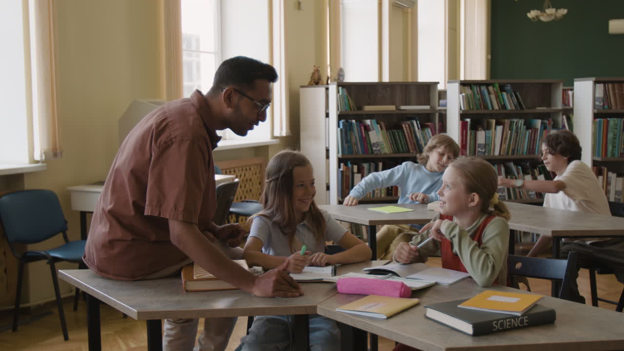 Teacher helping diverse students in a classroom or library setting