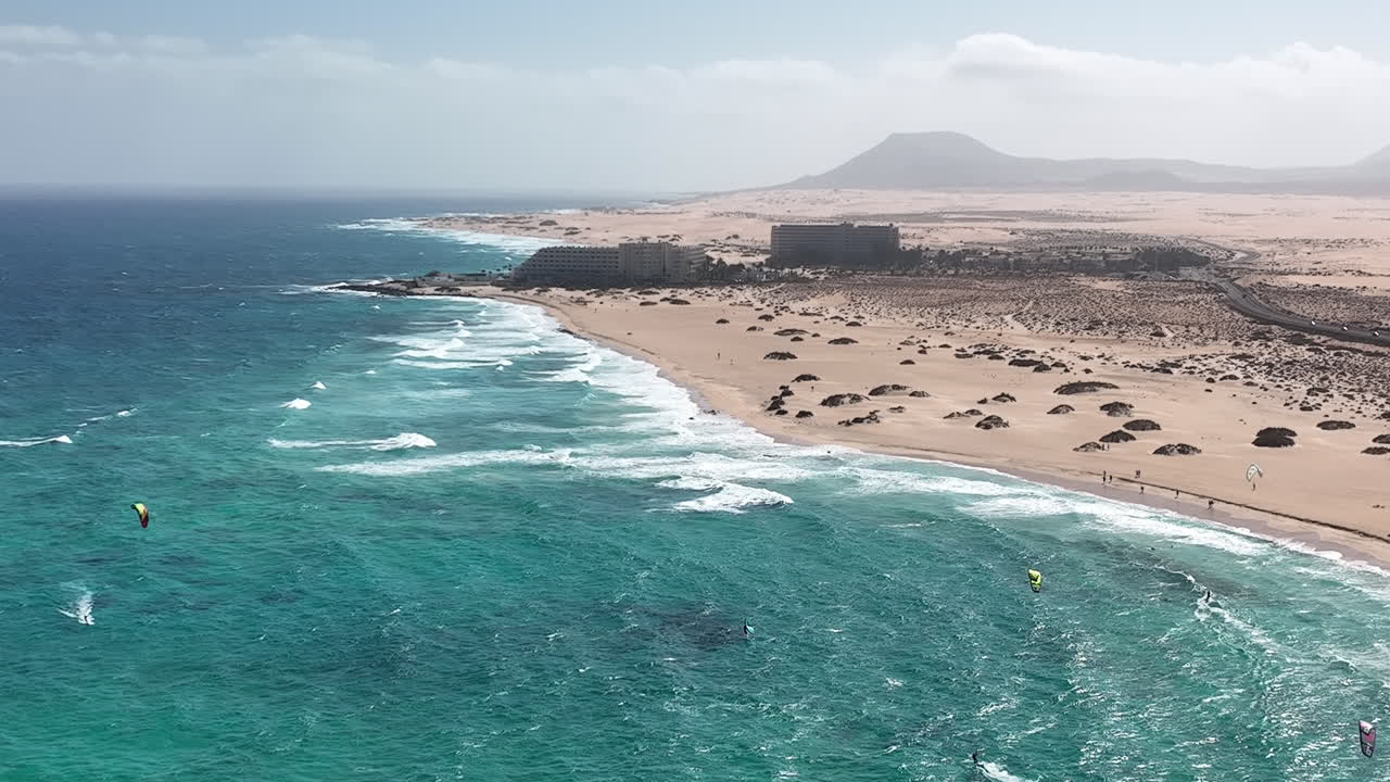Breathtaking views of Fuerteventura with Lobos Island, Red Flag Beach, kite surfers, sunsets, volcanoes, sand dunes, and wingfoilers in the Canary Islands’ golden light.