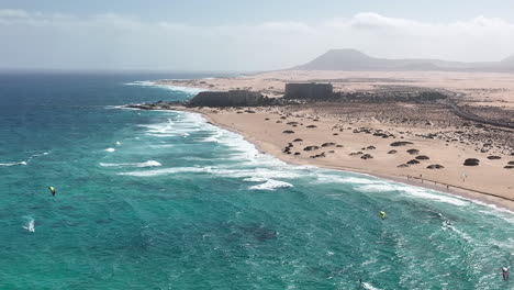 breathtaking views of fuerteventura with lobos island, red flag beach, kite surfers, sunsets, volcanoes, sand dunes, and wingfoilers in the canary islands’ golden light.