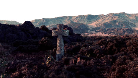 cruz de piedra en una colina en un paisaje montañoso