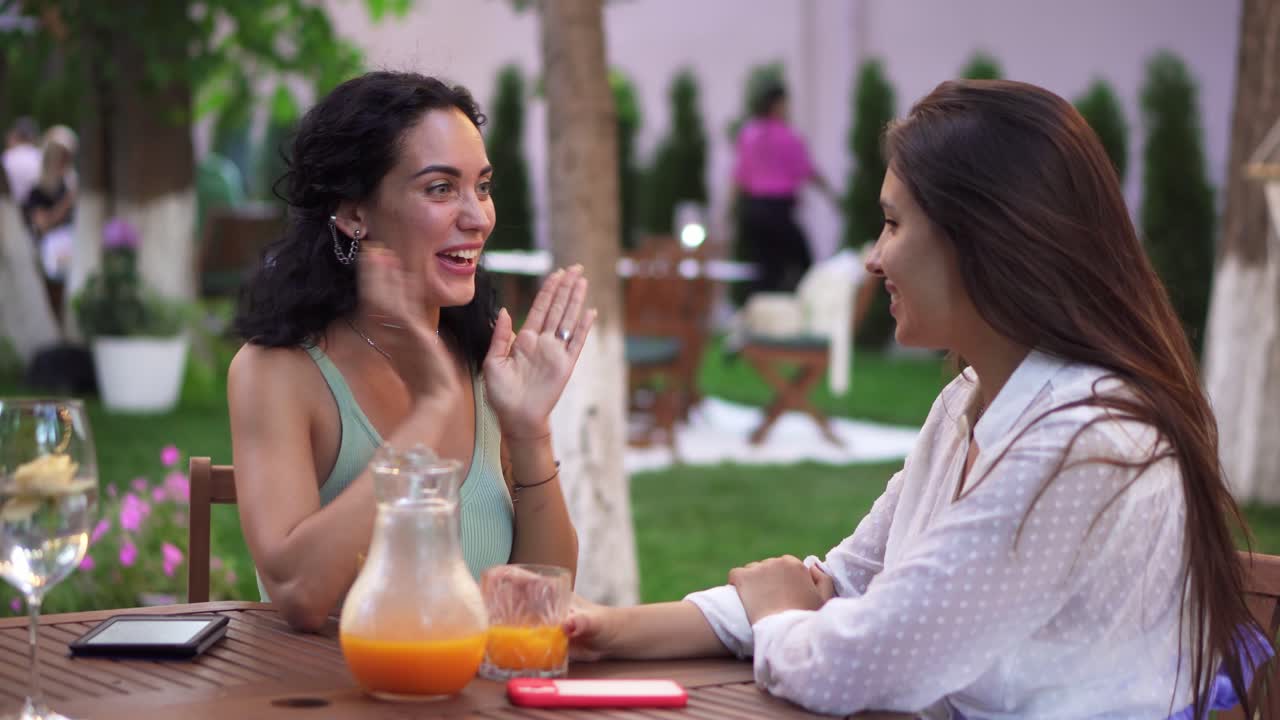 personas, comunicación y concepto de amistad - mujeres jóvenes sonrientes hablando en un café al aire libre, morena compartiendo buenas noticias
