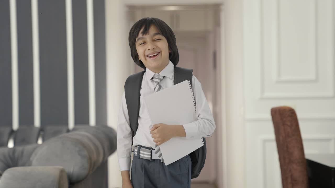 幸せなインド人の学校の少年が本を持って立っています