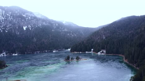 Vista-Aérea-De-Un-Impresionante-Lago-Congelado-Bajo-Los-Alpes-Con-Las-Islas-En-La-Nieve