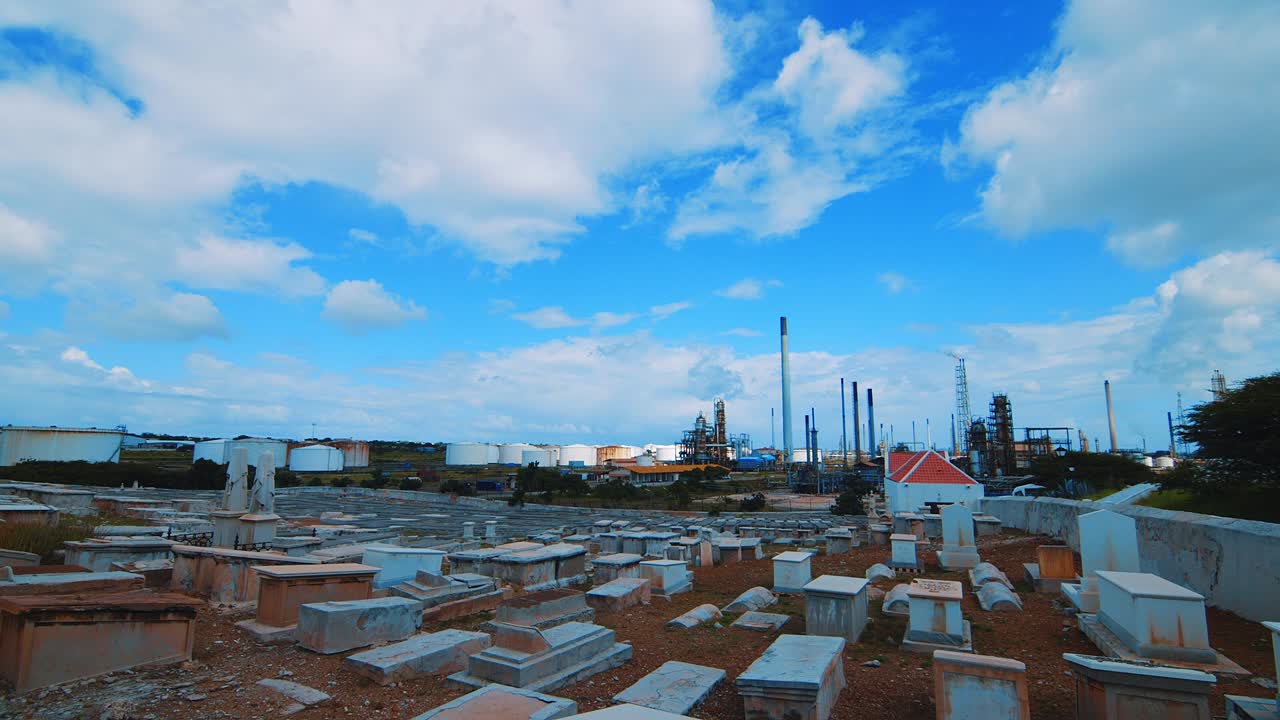 lapso de tiempo de un cementerio vacío con una gran refinería industrial en el fondo