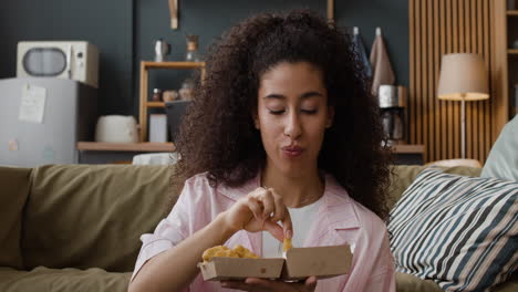 young woman enjoying a snack on the couch