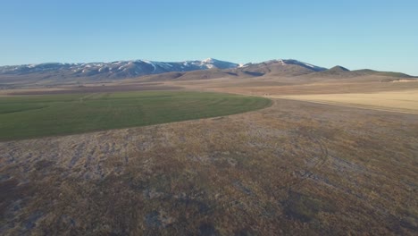 aerial view of farmland with snow-capped mountains in the background