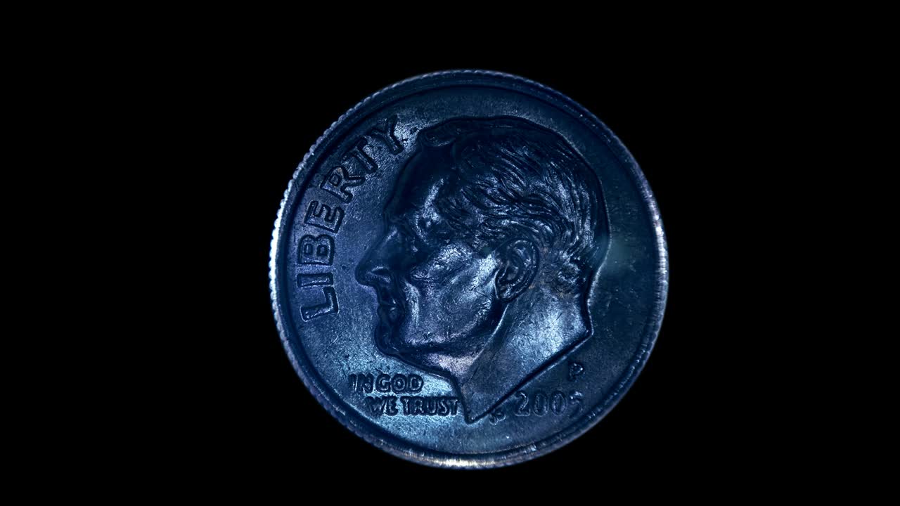 sobre un fondo negro, una moneda de diez centavos brilla en los rayos de luz