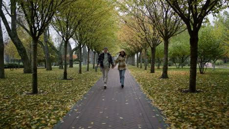 zoom shot of happy young lovers running with holding hands along path.