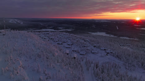 aerial tracking shot of snowy cabins on the iso-syote fell, sunrise in finland