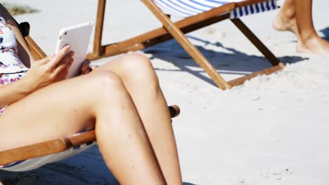 beautiful woman listening to music on digital tablet at beach