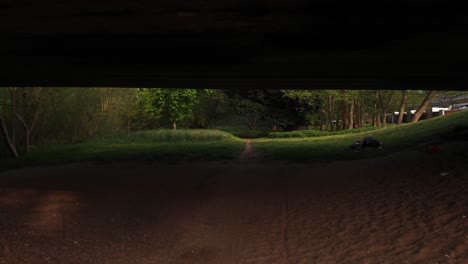 slow low drone clip flying under a concrete bridge towards a narrow path in thetford, england