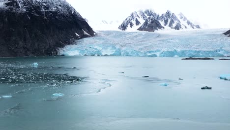 Arktische-Gletscher-Mit-Bergen-Im-Hintergrund-Und-Einem-Boot,-Das-Sich-Im-Wasser-Spiegelt