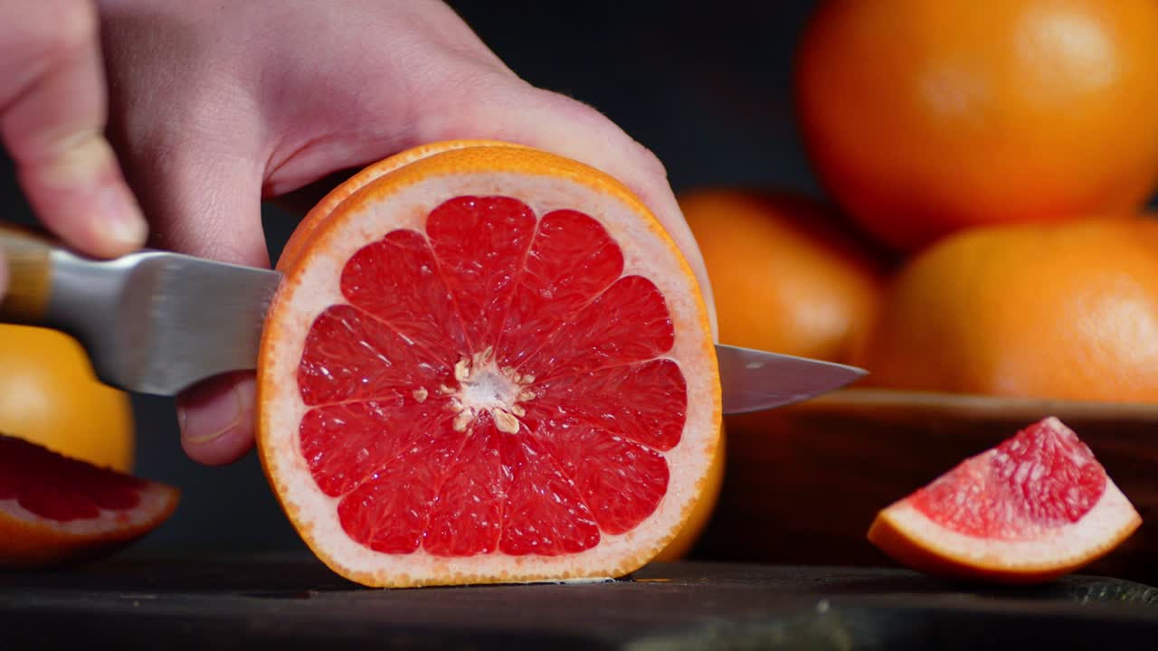 Hands men cut the grapefruit into round slices.