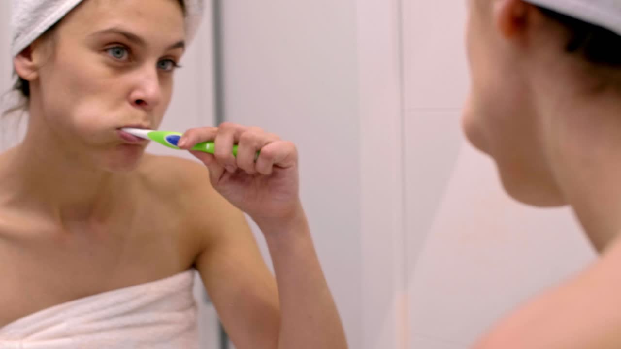 mujer joven limpiando los dientes en el baño