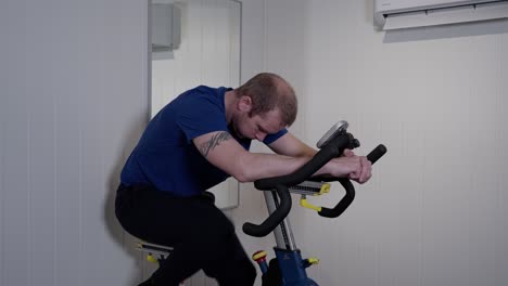 caucasian middle aged man riding indoor bike in his home gym