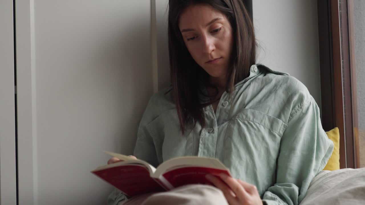 mujer leyendo un libro junto a la ventana