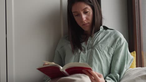 woman reading a book by the window