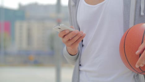 Hombre-Con-Una-Pelota-De-Baloncesto-Sosteniendo-Un-Teléfono-Inteligente---Cerrar