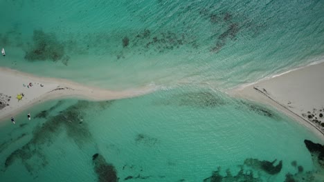 a sandbar connecting two islands in turquoise waters , aerial view