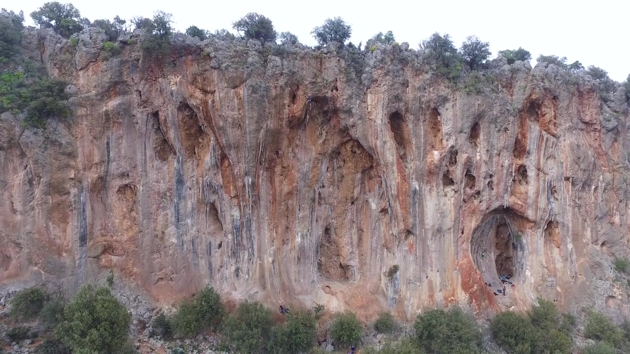 Scalatori di roccia che si arrampicano su una grande falesia calcarea