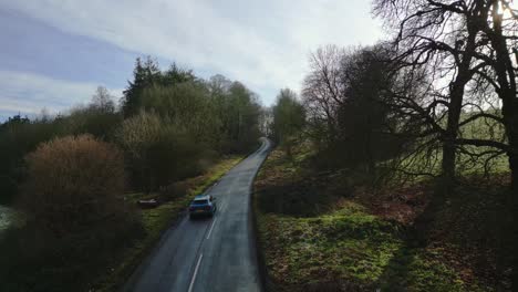 Luftdrohnenaufnahme-Eines-Autos-Auf-Einer-Britischen-Landstraße-Im-Winter-Bei-Sonnenuntergang