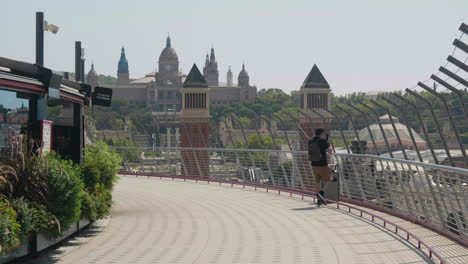 man walking at terrace of arenas de barcelona with venetian towers and palau nacional in background in barcelona, spain