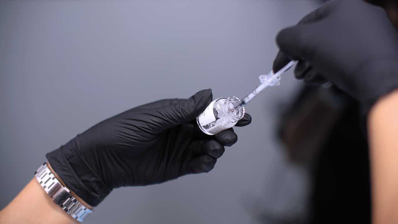 Botox is drawn out by syringe from an open glass Botox bottle