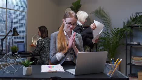 Cunning-young-businesswoman-rubbing-hands-scheming-evil-tricky-prank-plan-in-mind-in-office-interior