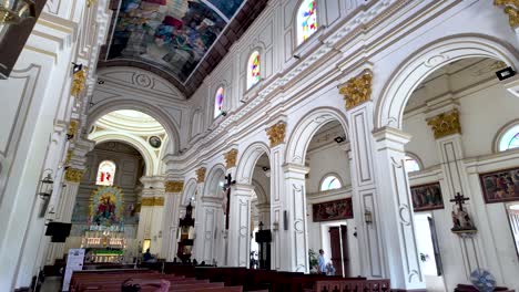 tourists are admiring the interior of st. mary's church, a roman catholic church in negombo, sri lanka, with its beautiful frescoes and stained glass